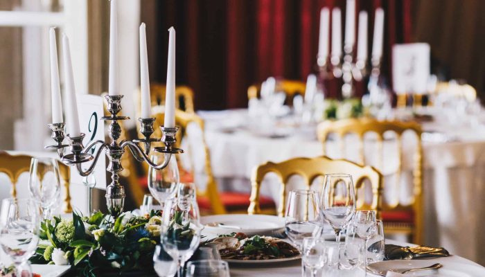 Close up of table served for festive dinner, decorated with candlestick, plates, glasses and flowers. Banquet table with dish in luxurious restaurant. Table setting for people on special occasion